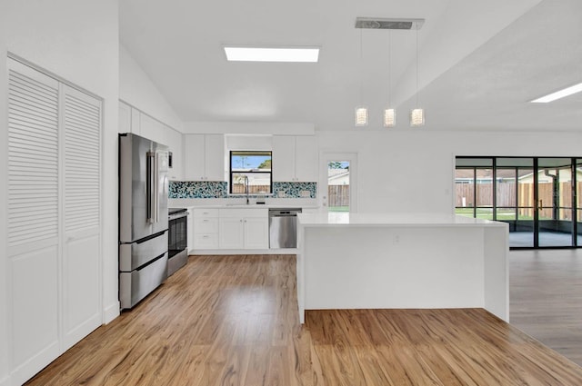 kitchen featuring pendant lighting, white cabinets, stainless steel appliances, and light wood-type flooring