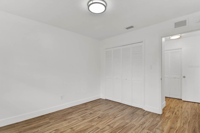 unfurnished bedroom with a closet and light wood-type flooring