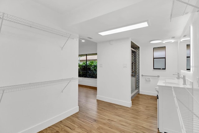 interior space with toilet, a shower with door, vanity, and hardwood / wood-style flooring