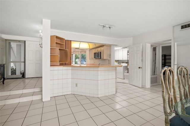 kitchen with kitchen peninsula, light tile patterned flooring, and independent washer and dryer