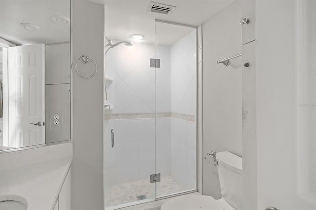 bathroom featuring a shower with door, vanity, and toilet