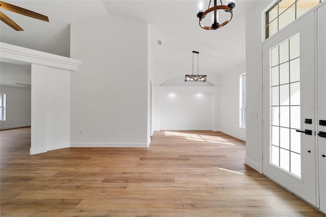 entryway featuring ceiling fan with notable chandelier, french doors, high vaulted ceiling, and light hardwood / wood-style flooring