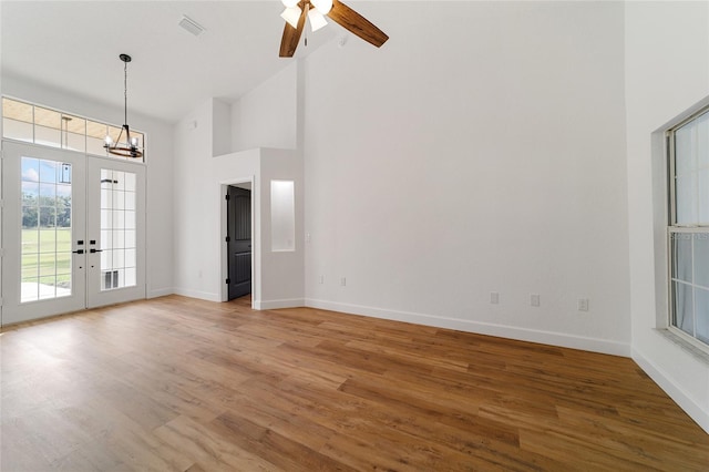 unfurnished living room with hardwood / wood-style flooring, ceiling fan, high vaulted ceiling, and french doors