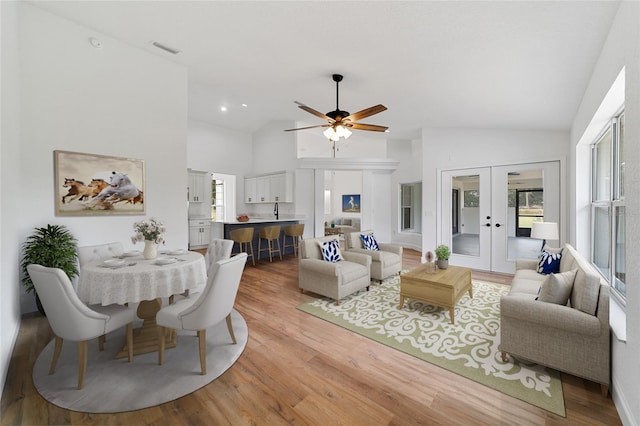 living room with french doors, vaulted ceiling, light hardwood / wood-style flooring, and ceiling fan