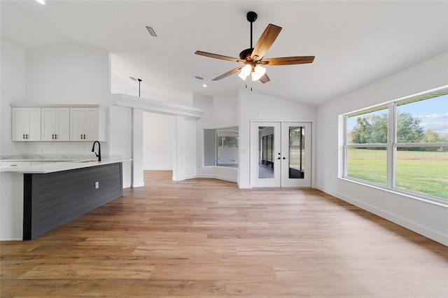 unfurnished living room with french doors, vaulted ceiling, and light hardwood / wood-style flooring