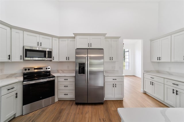 kitchen with white cabinetry, light hardwood / wood-style floors, and appliances with stainless steel finishes