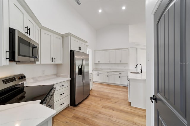 kitchen with sink, light hardwood / wood-style flooring, lofted ceiling, white cabinets, and appliances with stainless steel finishes