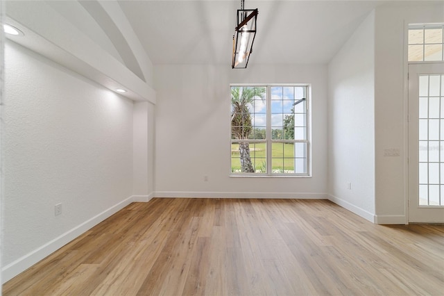 unfurnished dining area featuring light hardwood / wood-style floors and vaulted ceiling