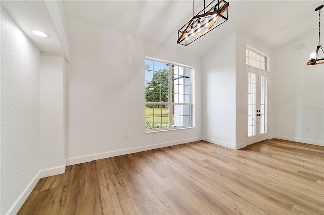 interior space with french doors, an inviting chandelier, lofted ceiling, and light wood-type flooring