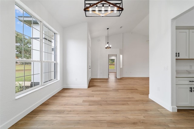 foyer featuring a chandelier, lofted ceiling, and light wood-type flooring