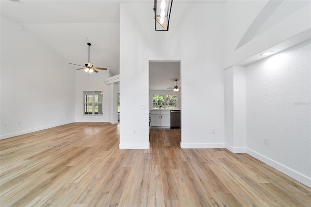 unfurnished living room with light hardwood / wood-style floors, high vaulted ceiling, ceiling fan, and sink