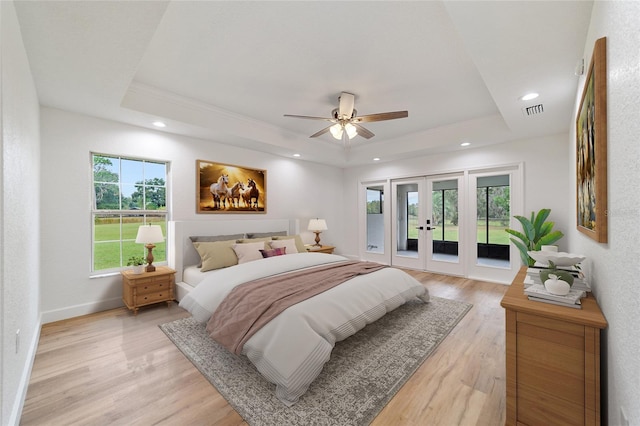 bedroom with french doors, access to outside, a tray ceiling, ceiling fan, and light hardwood / wood-style floors