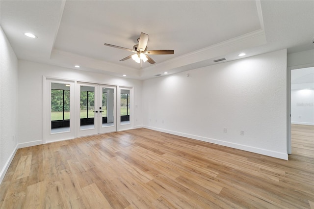 unfurnished room featuring ceiling fan, a raised ceiling, crown molding, and light hardwood / wood-style flooring