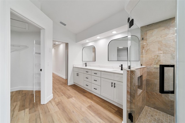 bathroom with a tile shower, vanity, vaulted ceiling, and hardwood / wood-style flooring