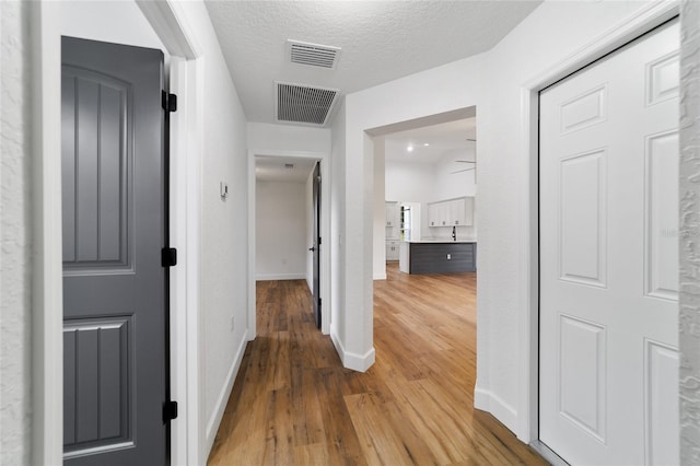 hall with hardwood / wood-style floors and a textured ceiling