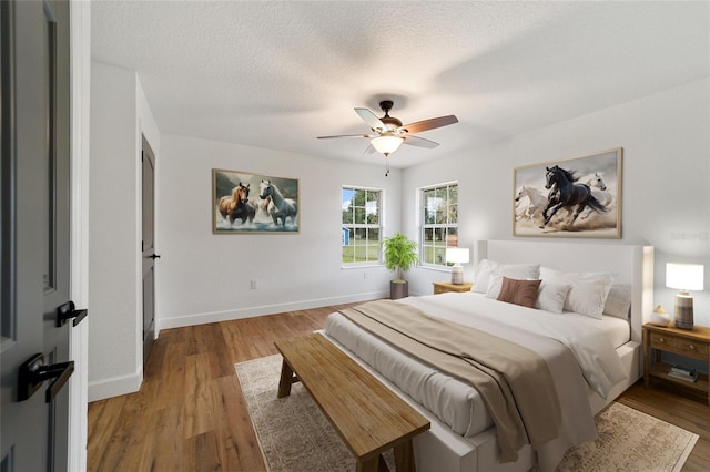 bedroom with a textured ceiling, light hardwood / wood-style flooring, and ceiling fan