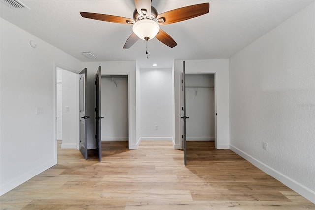 unfurnished bedroom with two closets, light hardwood / wood-style flooring, and ceiling fan