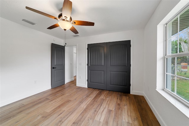 unfurnished bedroom with multiple windows, ceiling fan, and light hardwood / wood-style flooring