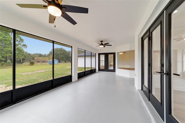 unfurnished sunroom featuring ceiling fan and french doors