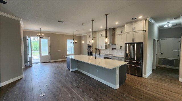 kitchen featuring a sink, appliances with stainless steel finishes, wall chimney exhaust hood, light countertops, and dark wood-style flooring