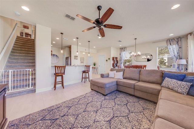 tiled living room featuring ceiling fan with notable chandelier