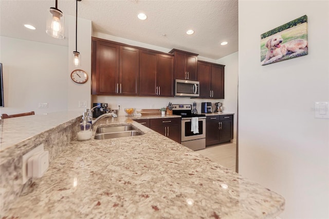 kitchen with pendant lighting, sink, a textured ceiling, dark brown cabinetry, and stainless steel appliances