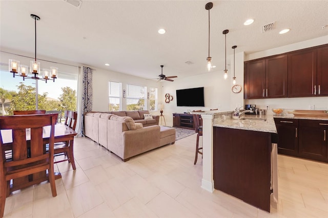 kitchen featuring kitchen peninsula, ceiling fan with notable chandelier, hanging light fixtures, and a breakfast bar