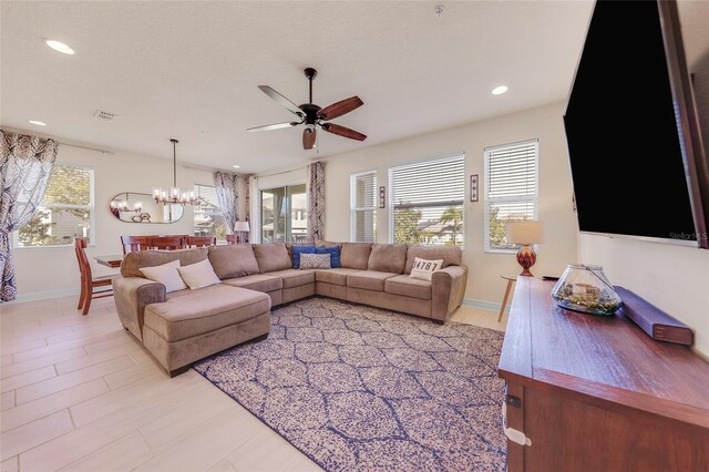 living room with ceiling fan with notable chandelier