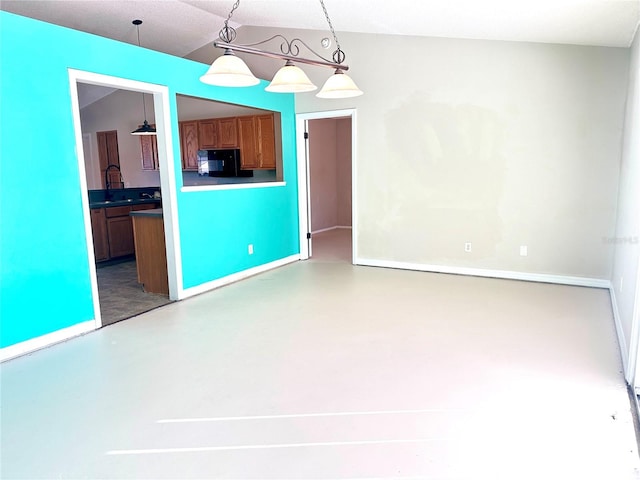 kitchen featuring black refrigerator, hanging light fixtures, and concrete floors