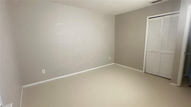 unfurnished bedroom featuring a closet, concrete floors, and a textured ceiling