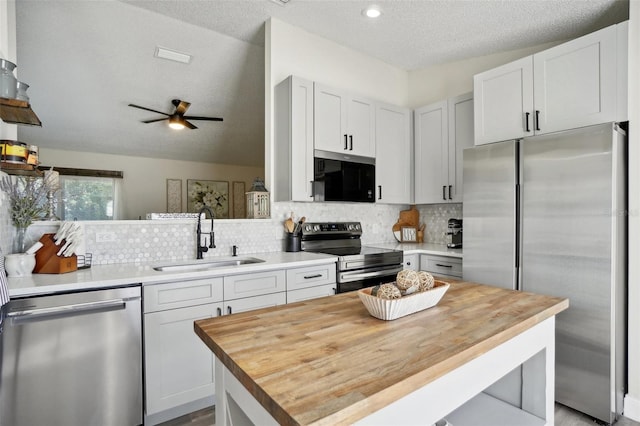 kitchen featuring sink, tasteful backsplash, a textured ceiling, white cabinets, and appliances with stainless steel finishes