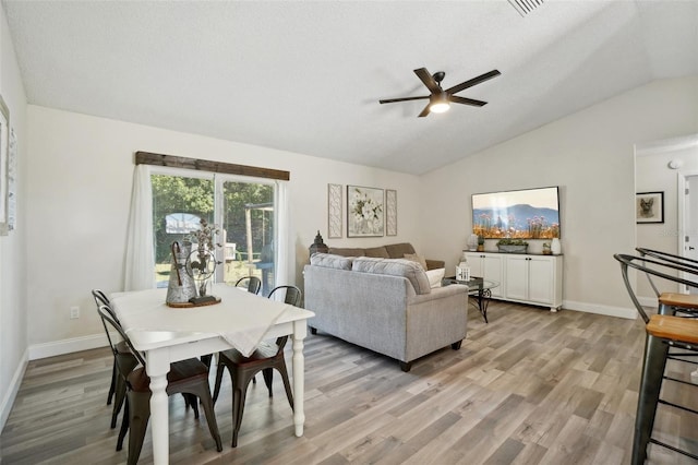 dining room with a textured ceiling, light wood-type flooring, ceiling fan, and lofted ceiling