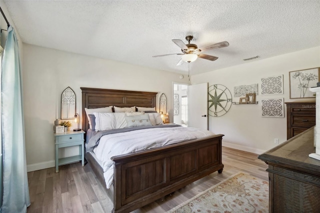 bedroom featuring ceiling fan, light hardwood / wood-style flooring, and a textured ceiling