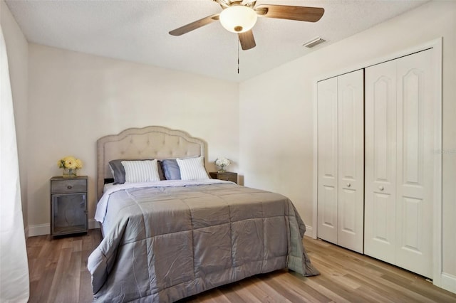 bedroom with hardwood / wood-style flooring, ceiling fan, a textured ceiling, and a closet