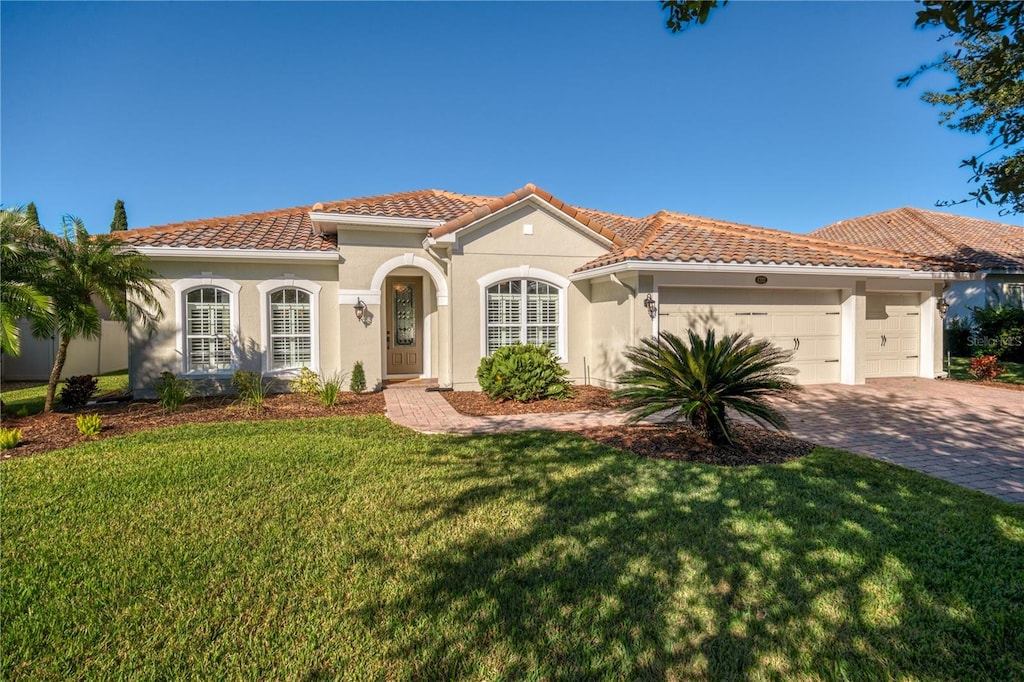 mediterranean / spanish home featuring a front yard and a garage