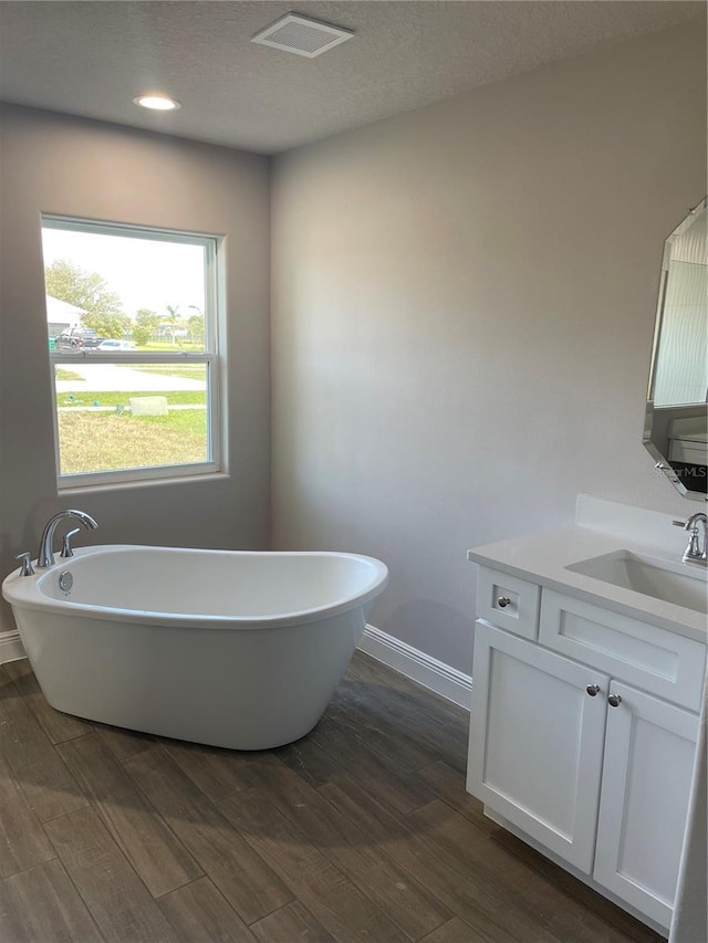 bathroom featuring hardwood / wood-style flooring, vanity, a textured ceiling, and a washtub