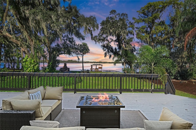 deck at dusk featuring an outdoor living space with a fire pit