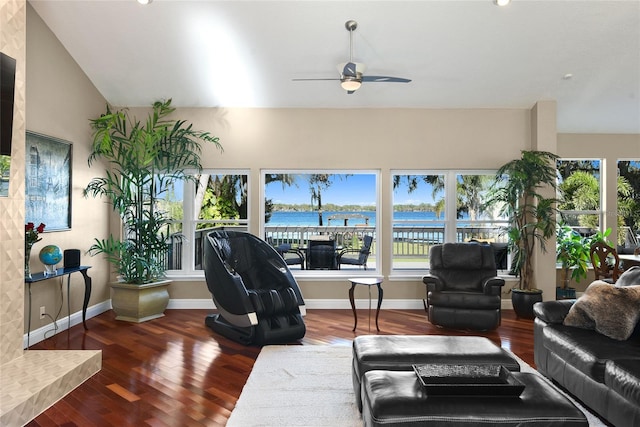 living room featuring dark hardwood / wood-style flooring, ceiling fan, a water view, and vaulted ceiling