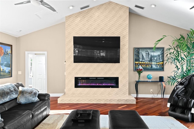 living room with wood-type flooring, ceiling fan, lofted ceiling, and a tiled fireplace