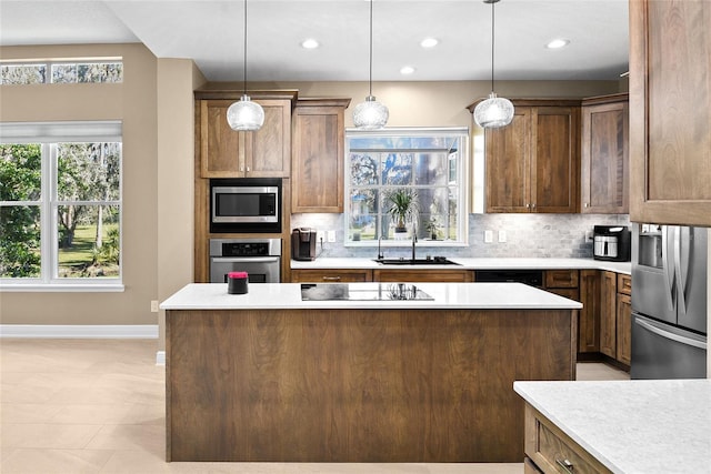 kitchen featuring sink, a center island, backsplash, pendant lighting, and appliances with stainless steel finishes