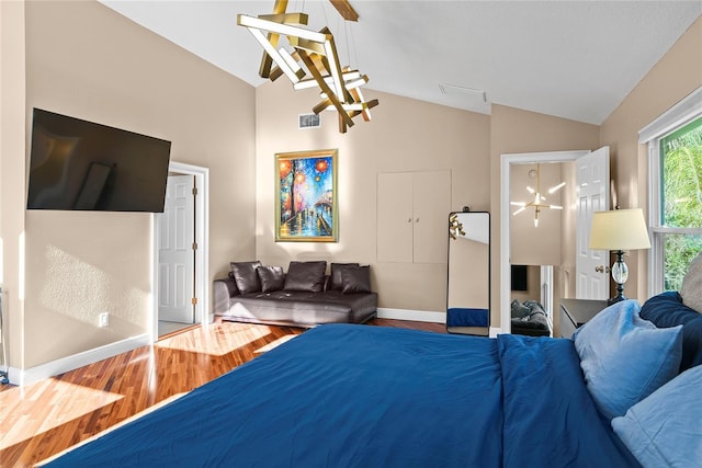 bedroom featuring hardwood / wood-style flooring, an inviting chandelier, and lofted ceiling