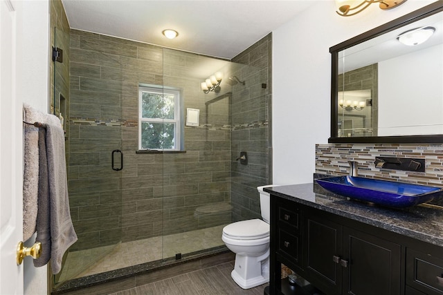 bathroom featuring backsplash, vanity, an enclosed shower, and toilet