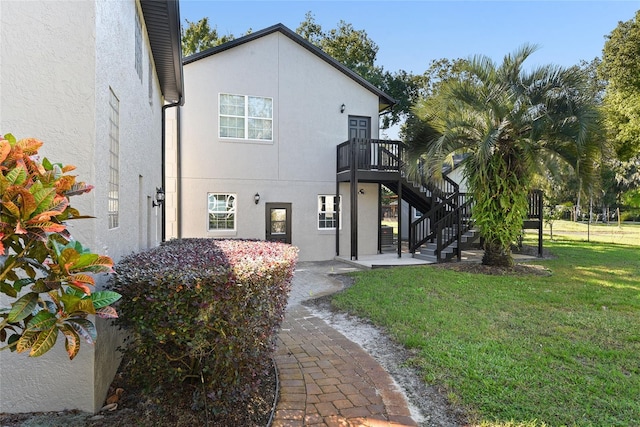 rear view of house featuring a lawn and a wooden deck