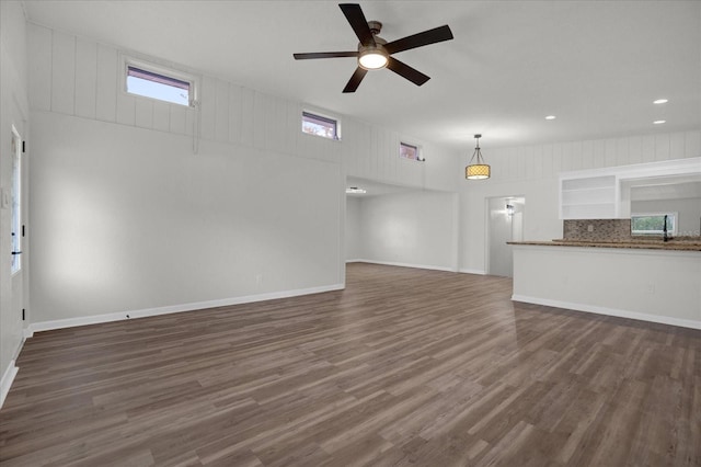 unfurnished living room featuring dark hardwood / wood-style floors, ceiling fan, and a wealth of natural light