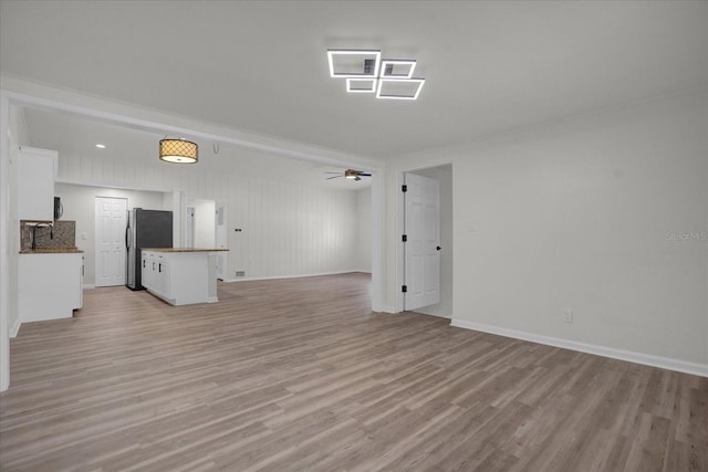 unfurnished living room featuring light hardwood / wood-style flooring, ceiling fan, and sink