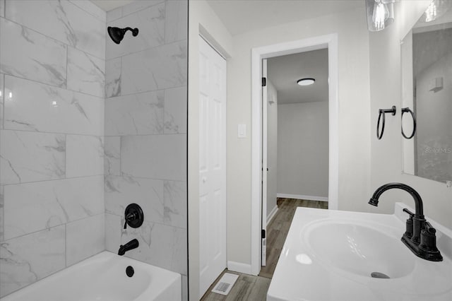 bathroom with tiled shower / bath combo, wood-type flooring, and vanity