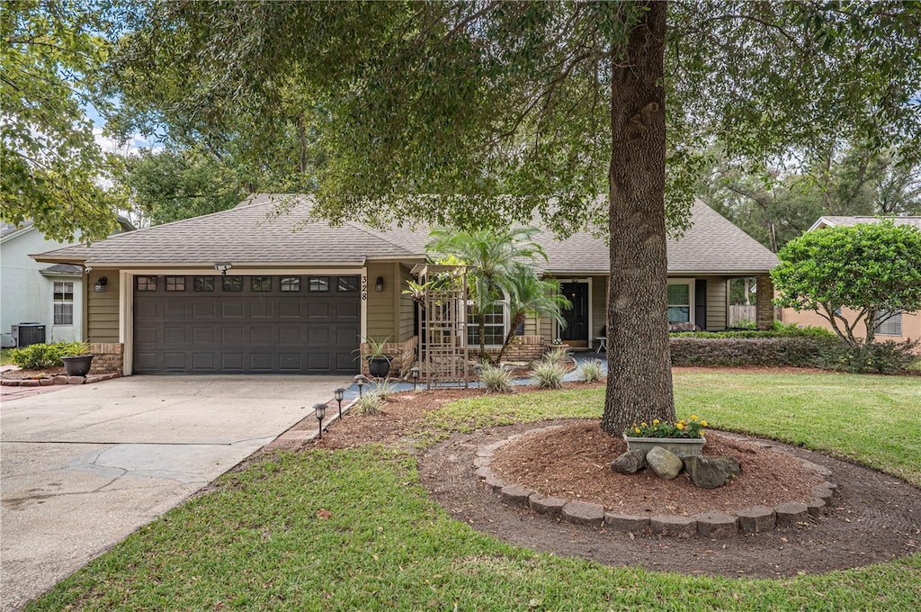 view of front of home with a garage, a front yard, and central air condition unit