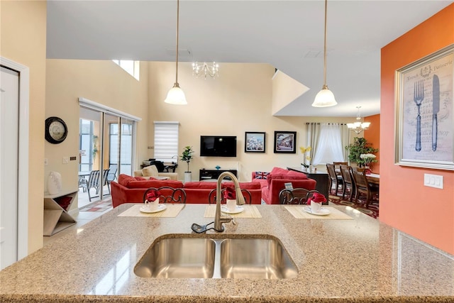 kitchen with light stone countertops, pendant lighting, an inviting chandelier, and sink