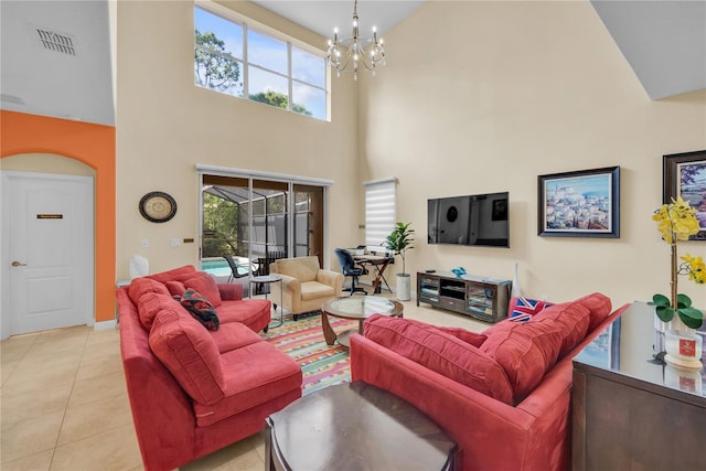 living room featuring a notable chandelier, light tile patterned floors, a towering ceiling, and a wealth of natural light