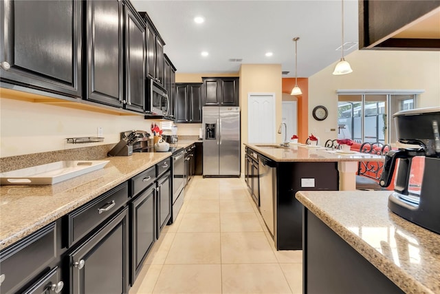 kitchen featuring light stone countertops, sink, decorative light fixtures, light tile patterned floors, and appliances with stainless steel finishes